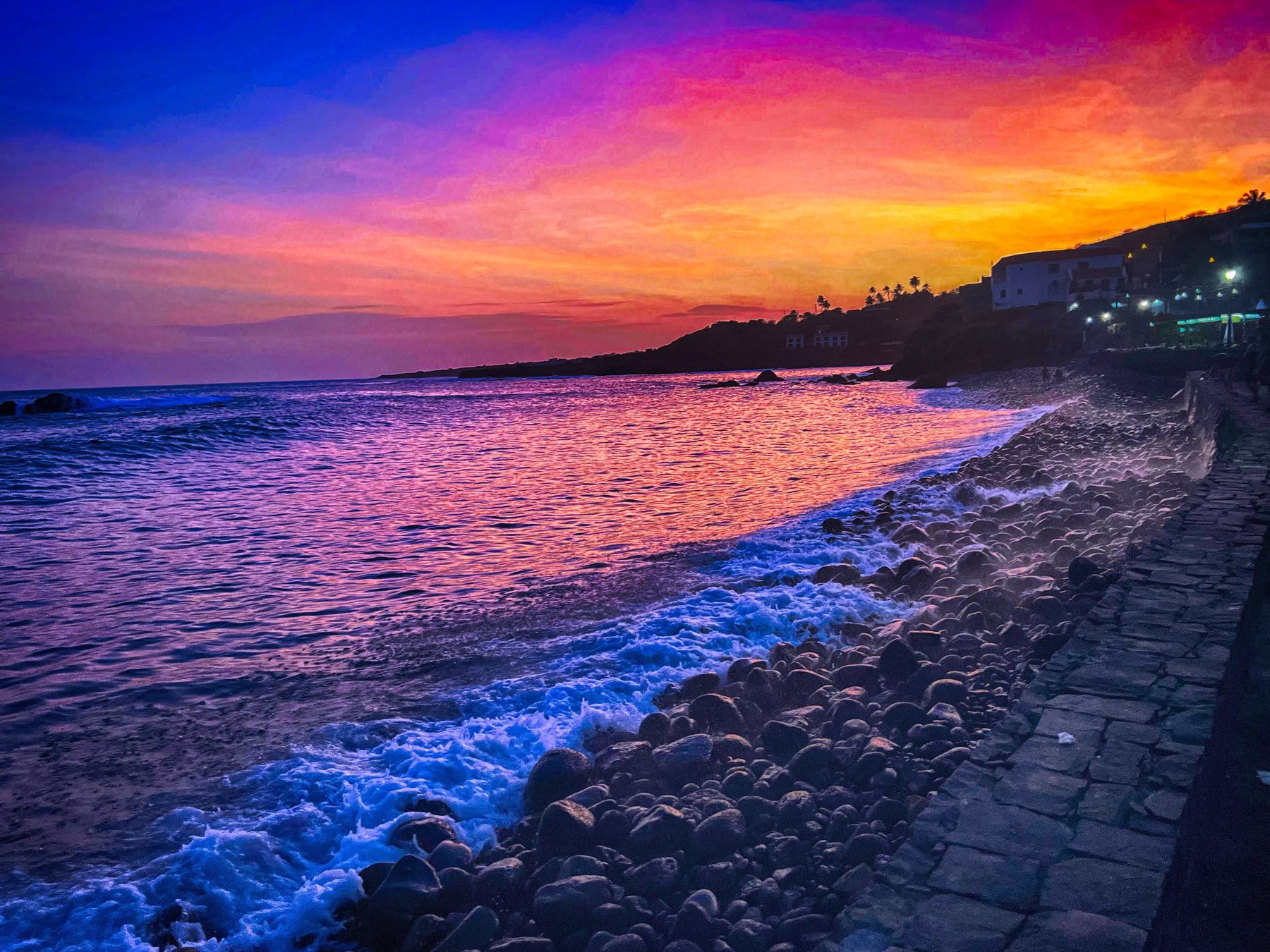 A violet and orange sunset over a pebble beach in Cabo Verde